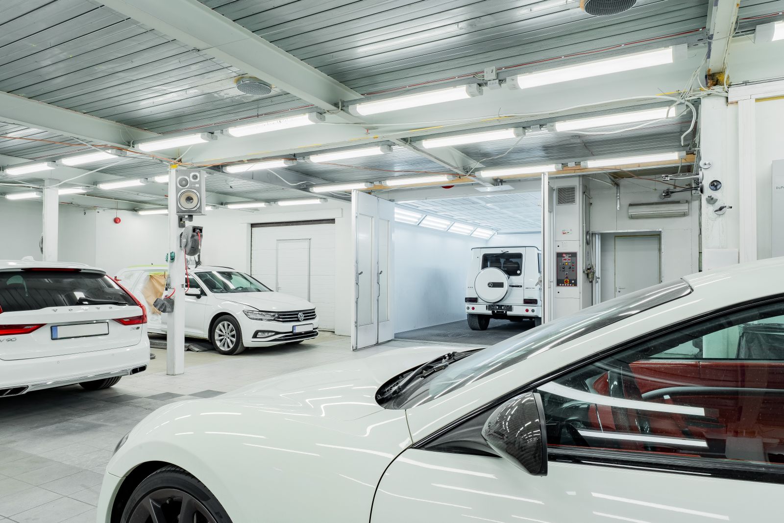 Bright, spacious car wash interior featuring multiple vehicles, showcasing clean and modern automotive environment.